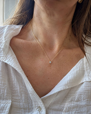 Colar dourado com ponto de luz, sobre uma camisa branca